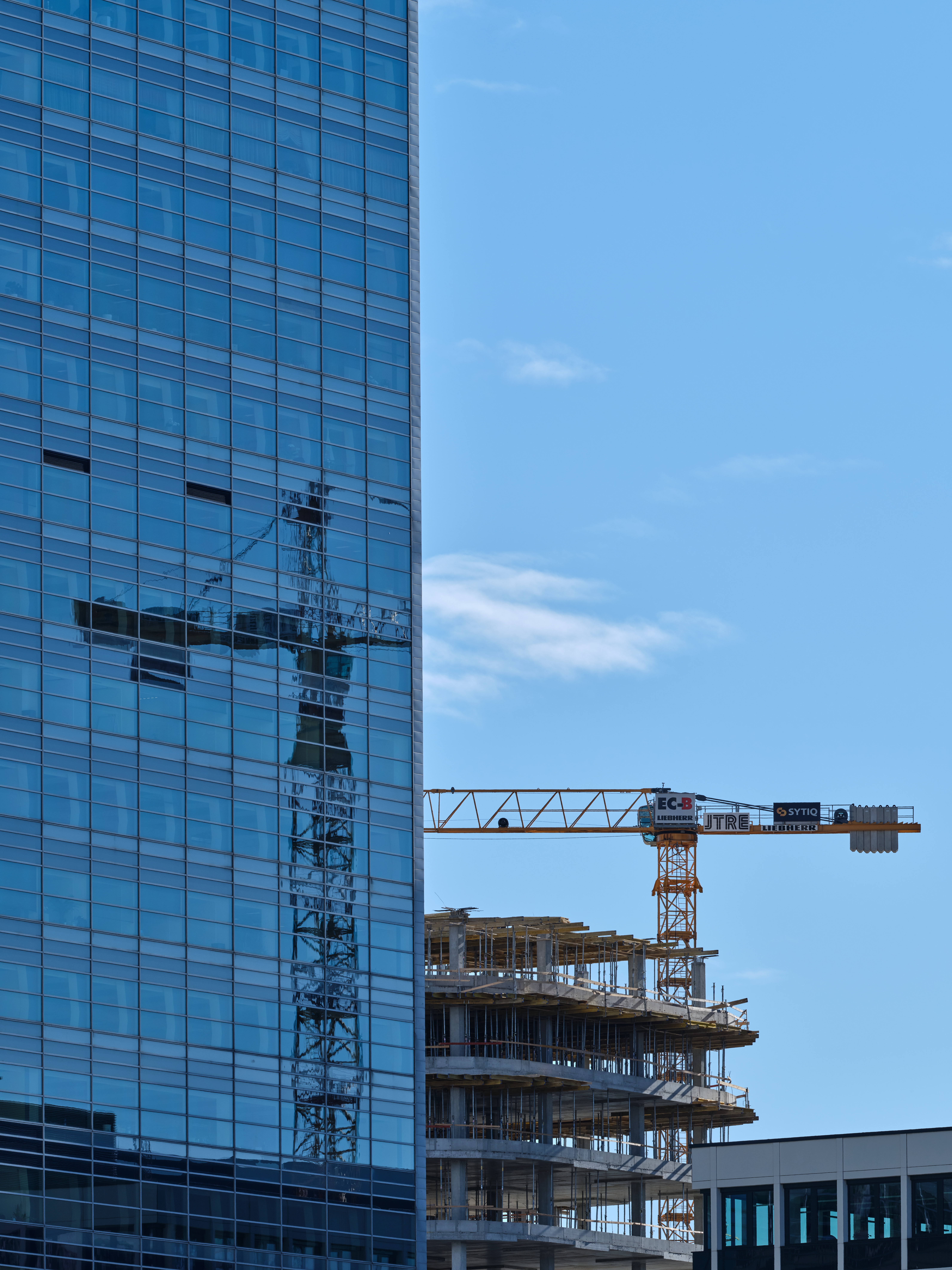photo of reflection of a crane on the glass windows of a building